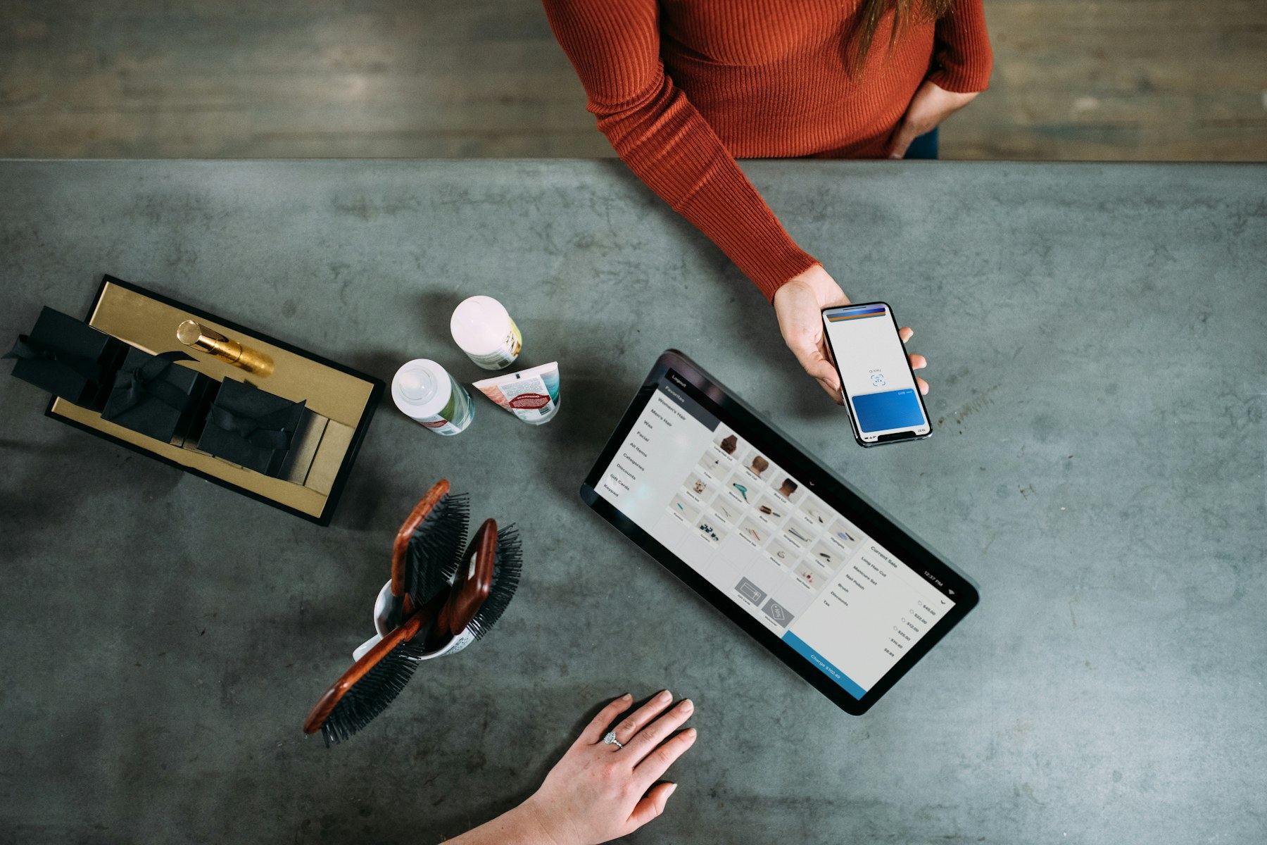 Retail worker and customer completing a mobile checkout with a smartphone and tablet point-of-sale system.