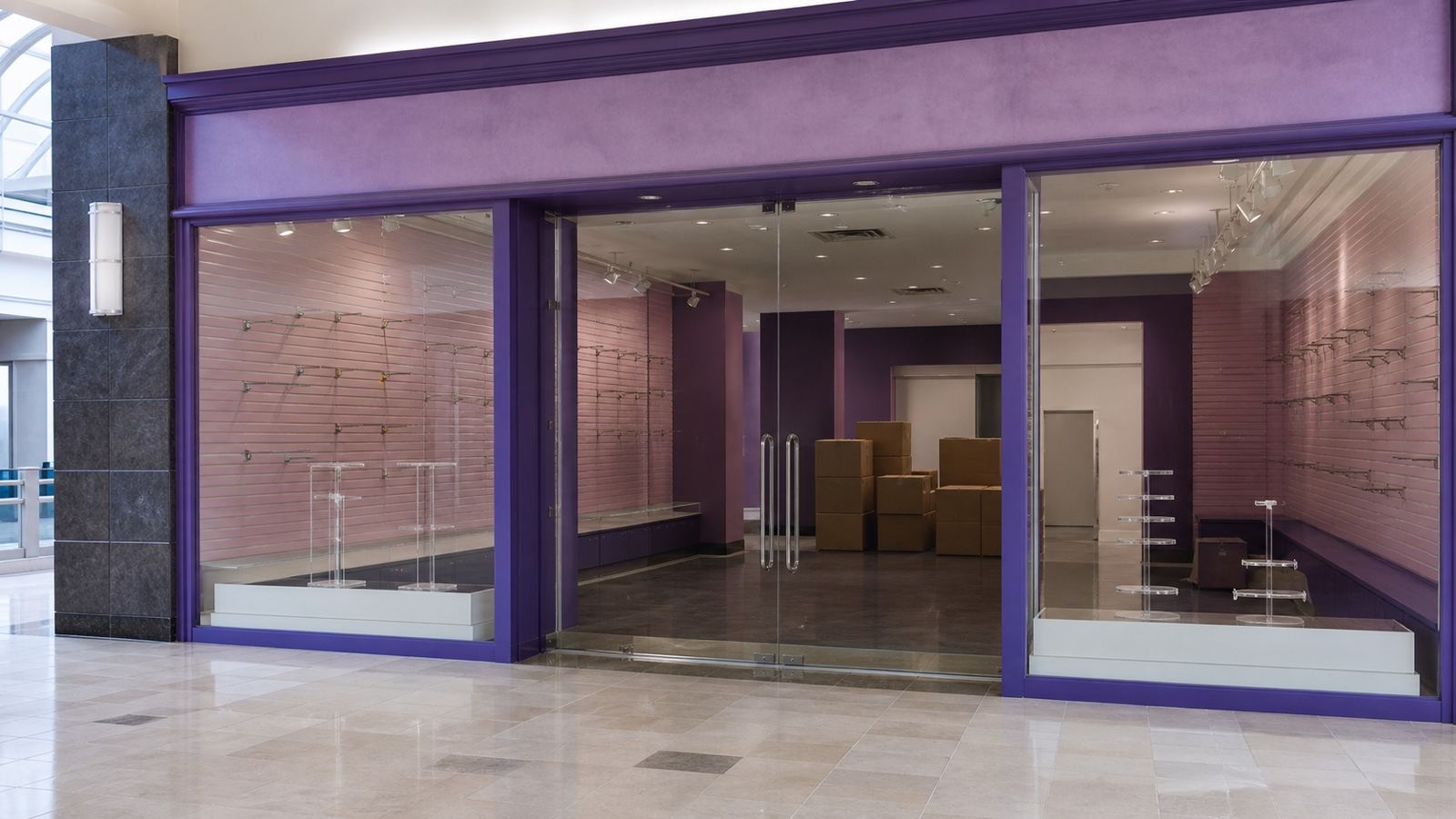 A logo-free empty purple mall accessories store with fixtures removed and boxes remaining.
