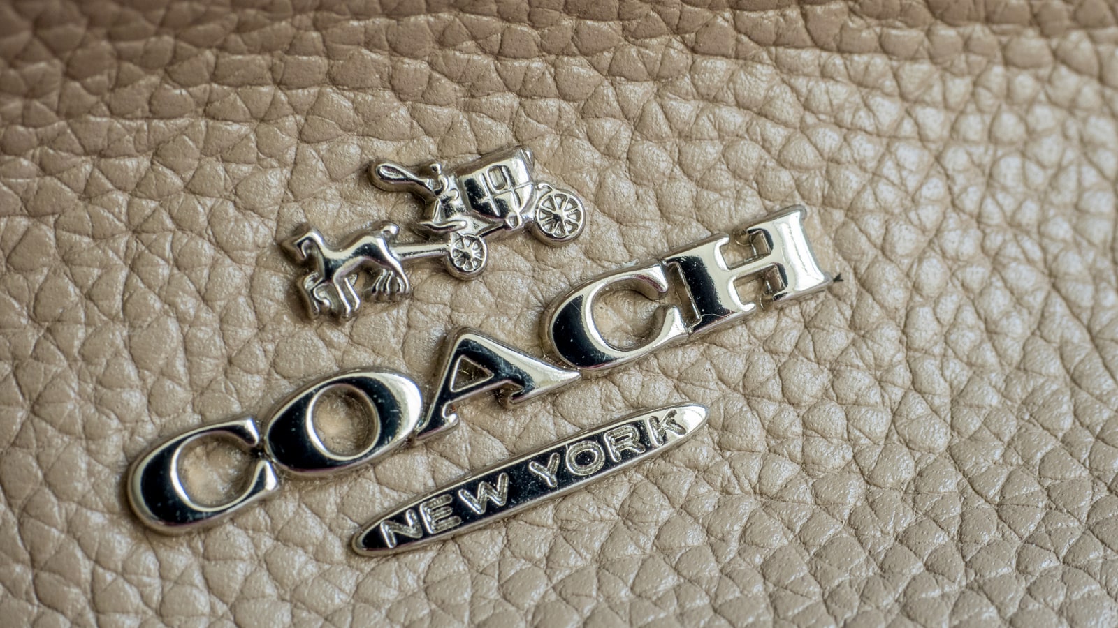 Coach New York logo hardware on leather texture.