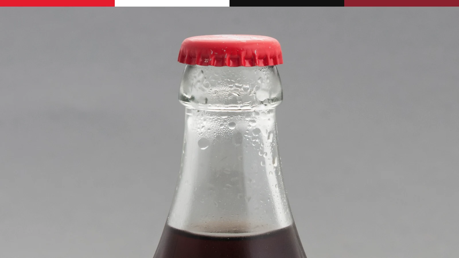 Cold Coca-Cola glass bottle with visible condensation and contour shape.