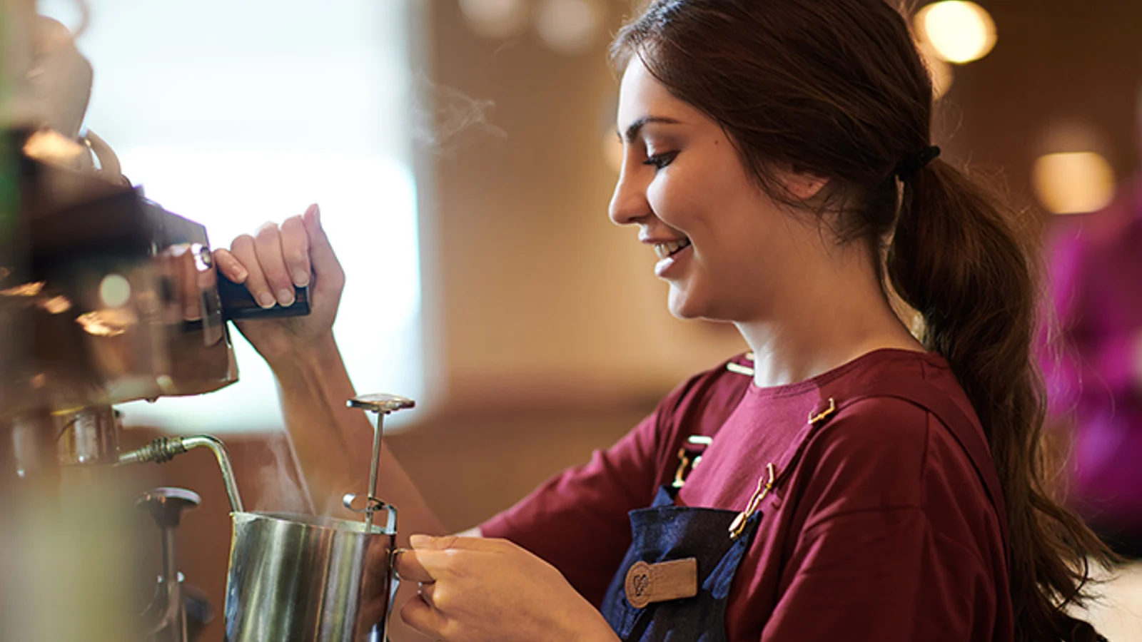 Costa Coffee barista preparing milk at an espresso machine.
