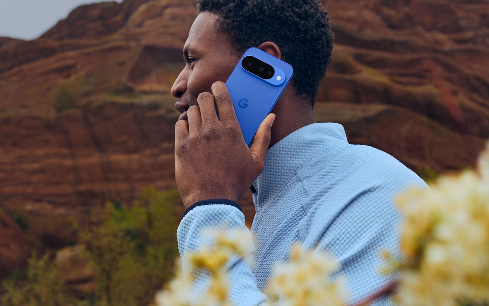 Official Google image showing a person using a blue Pixel phone outdoors.