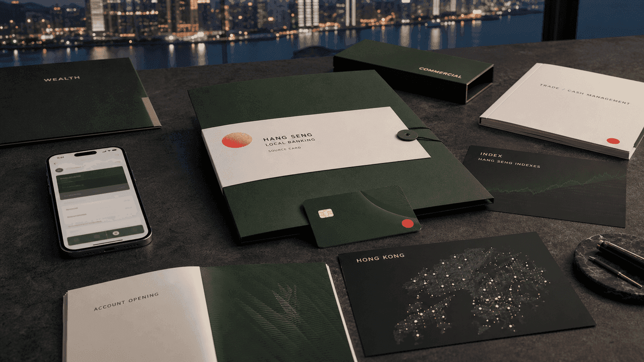 Premium AI-generated editorial table still-life for the Hang Seng Bank case with Hong Kong skyline, green source-card folder, blank bank card, mobile banking screen, wealth folder, commercial banking file, trade cash-management book, Hang Seng Indexes card, and branch network map