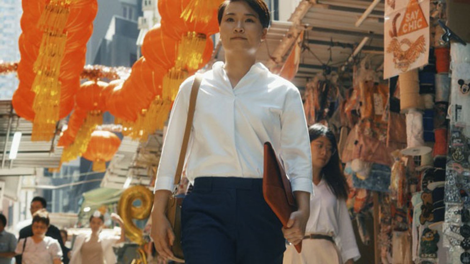 An HSBC mobile wealth manager walking through a Hong Kong market district with a client folder.