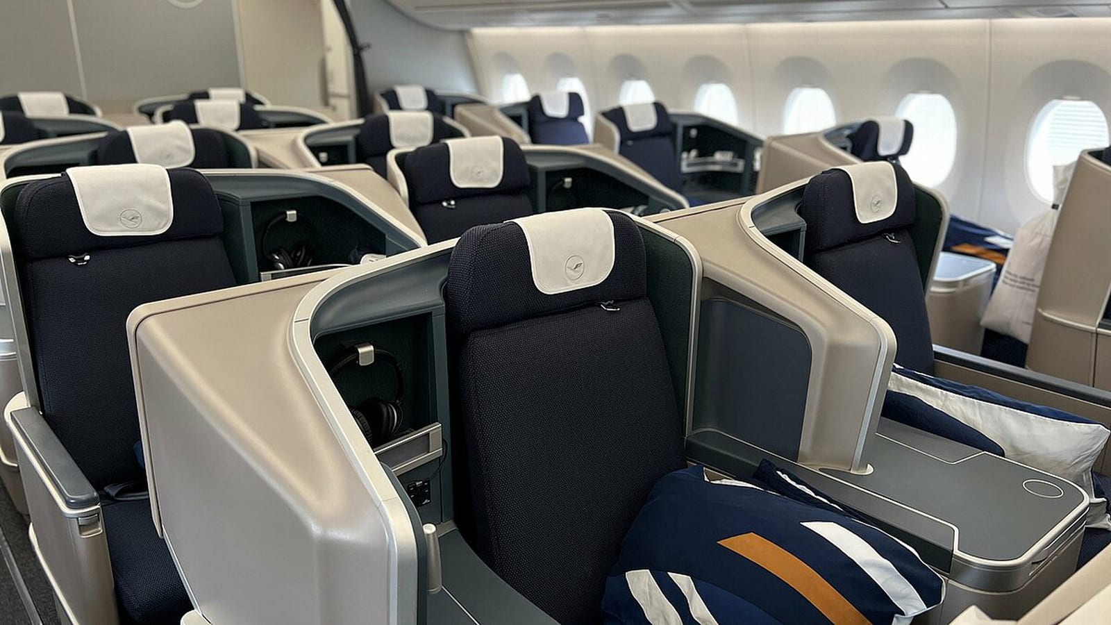 Lufthansa Airbus A350 business-class cabin with navy seats, direct aisle access, and crane-marked headrest covers.