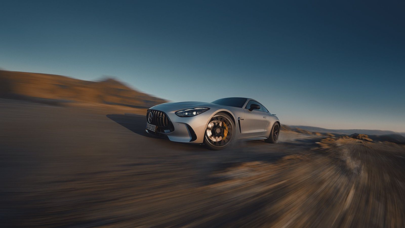 Official Mercedes-AMG GT coupe driving through a controlled desert performance scene.