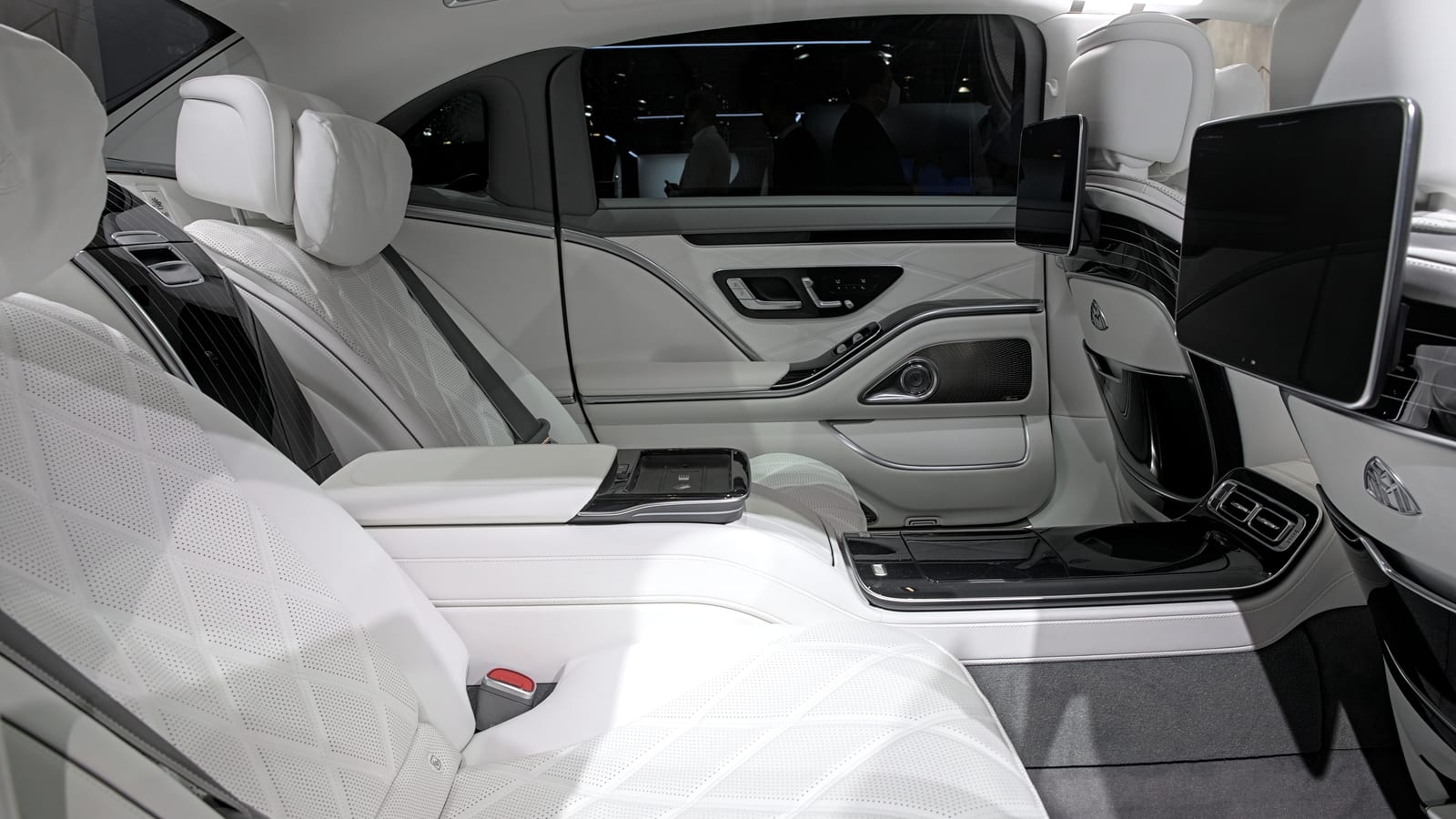 Mercedes-Maybach S-Class rear cabin with white leather, screens, and executive-seat detail.