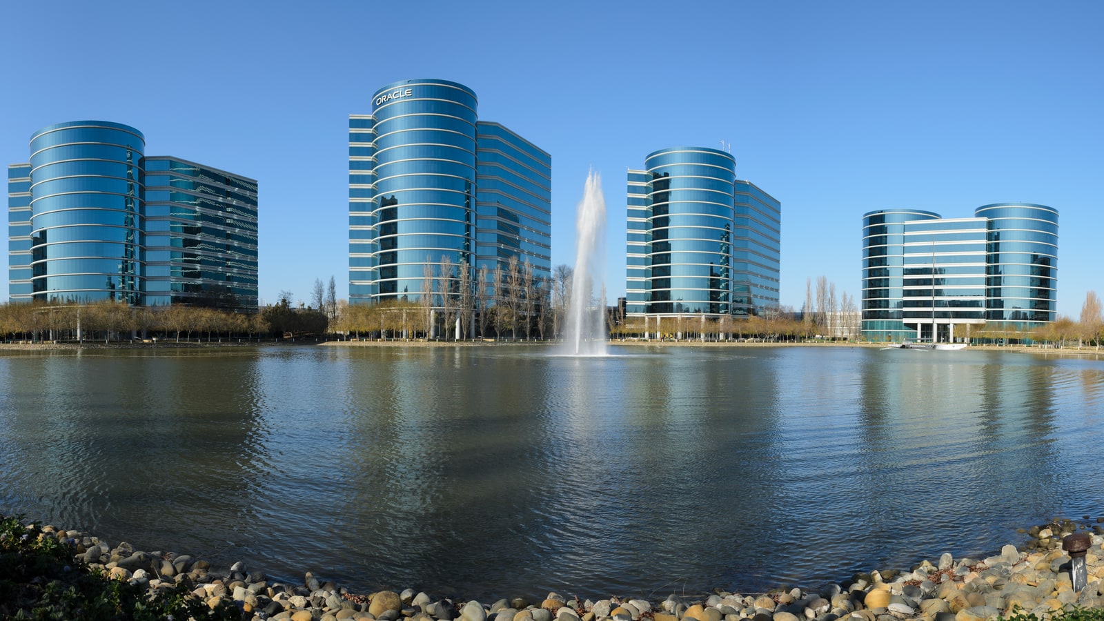 Oracle Redwood Shores campus buildings reflected across the lagoon.