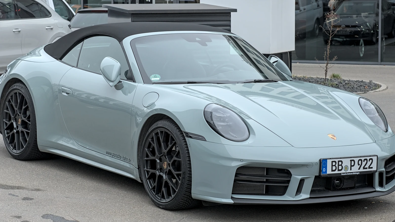 Current-generation Porsche 911 Carrera parked near a showroom.