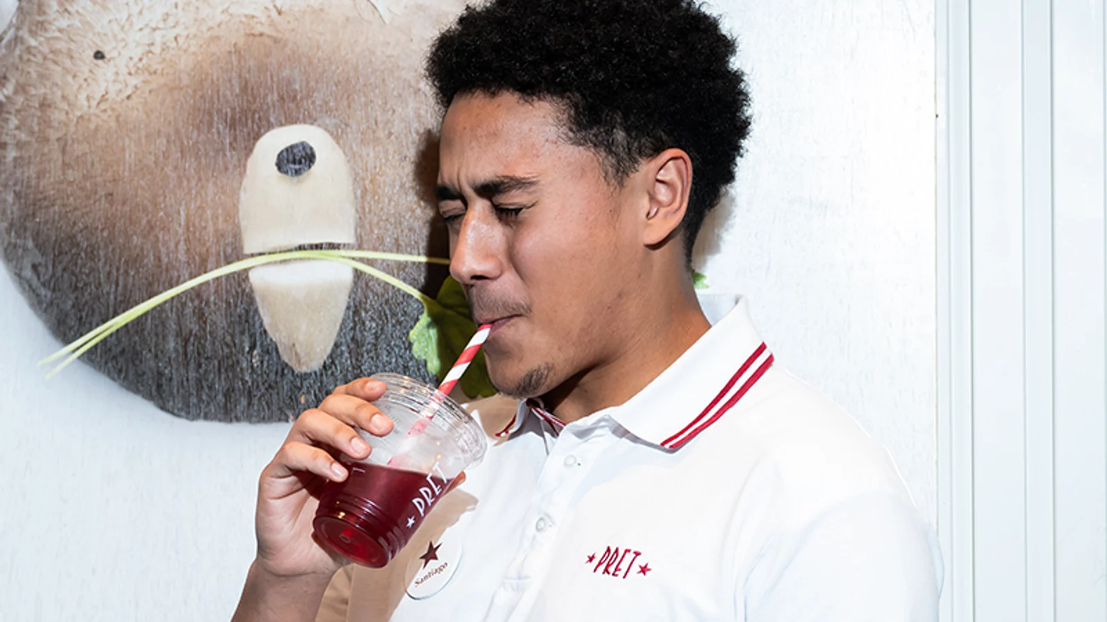 Pret team member holding a branded drink in a shop.