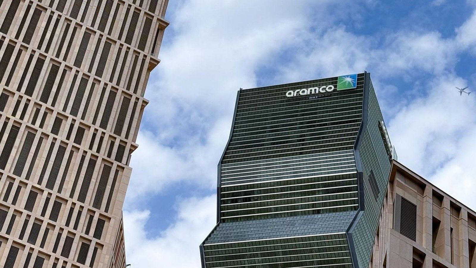 Saudi Aramco tower photographed from street level with the Aramco sign visible on the high-rise.