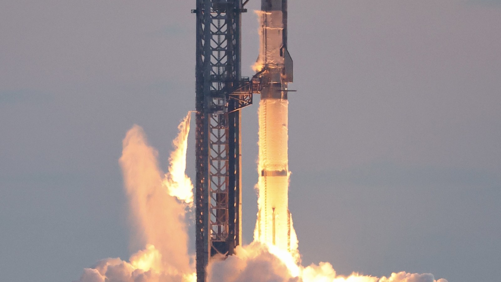 SpaceX Starship ignition with launch tower and vehicle visible.