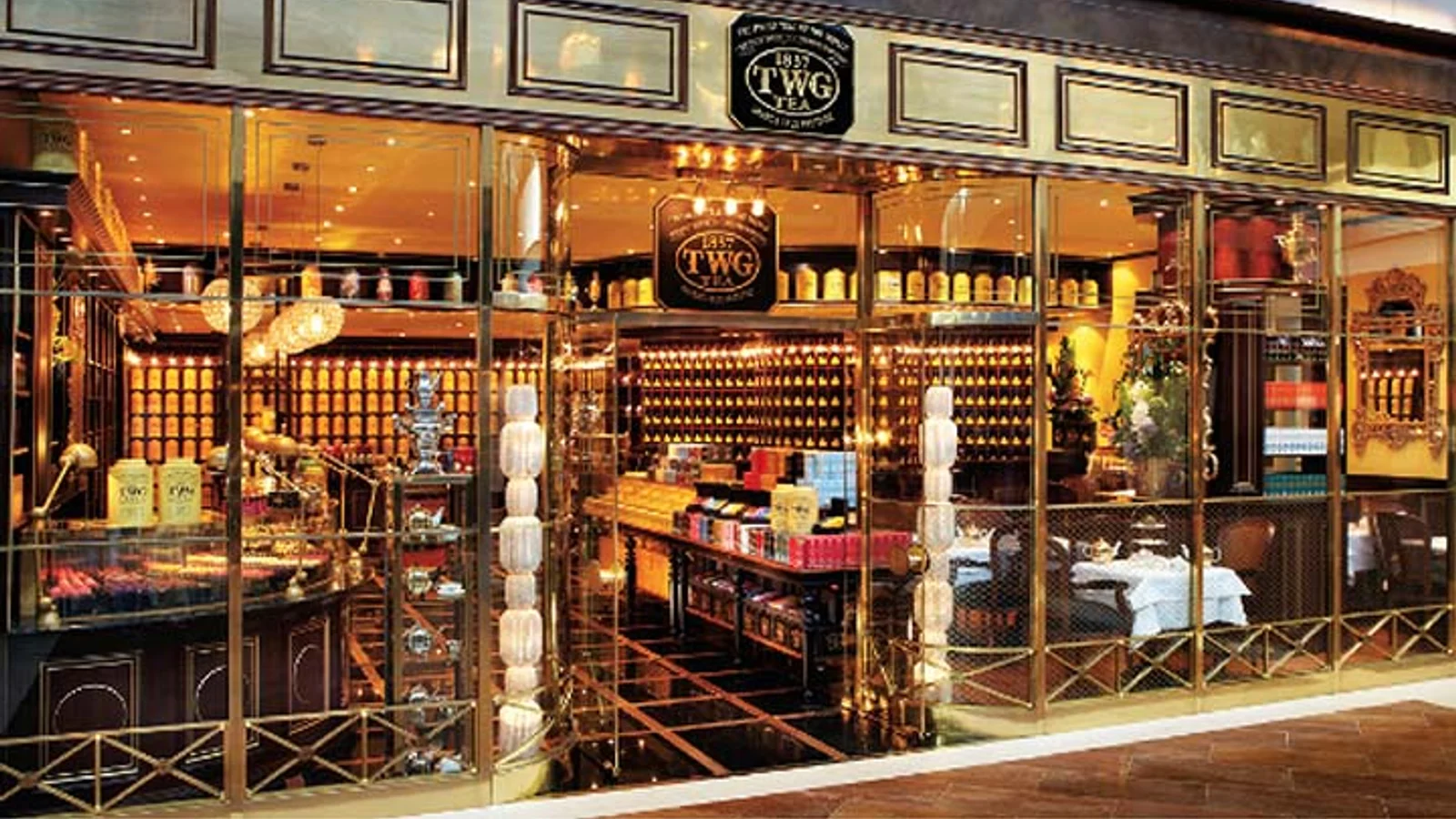 TWG Tea boutique storefront and salon with gold tins and dark cabinetry.