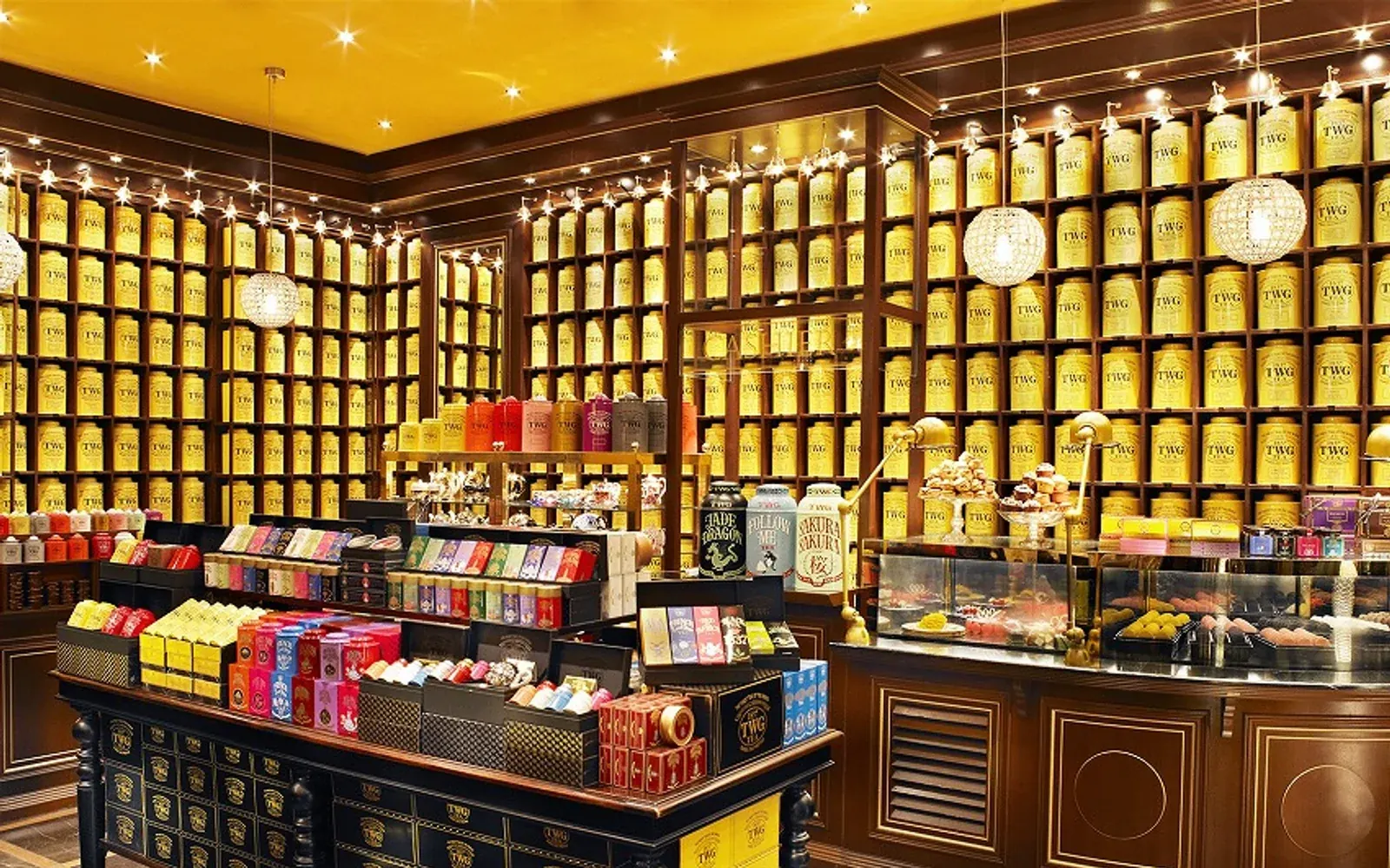 TWG Tea boutique interior with gold tea tins, dark cabinetry, and salon presentation.