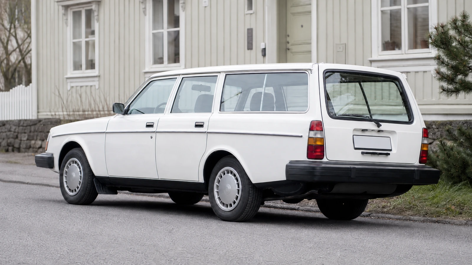 Logo-free white boxy Scandinavian estate car beside restrained Nordic architecture.