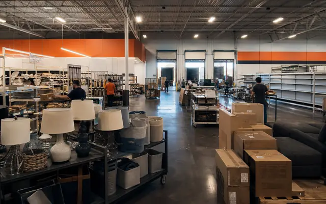 A large discount home-goods store between liquidation and restocking, with mixed merchandise, empty shelving, and reset workers.