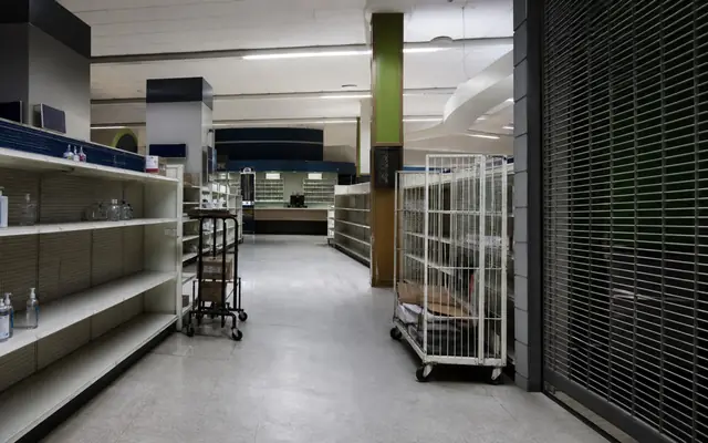 A sparse pharmacy retail interior with empty shelves and a closed security gate after the legacy Rite Aid chain wound down.