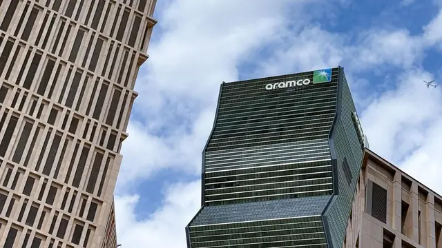 Saudi Aramco tower photographed from street level with the Aramco sign visible on the high-rise.